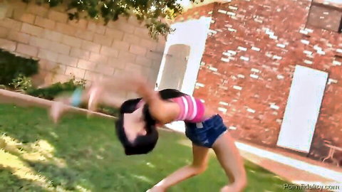 Amia Miley in flexible outdoor backbend pose in pink tank top and denim shorts
