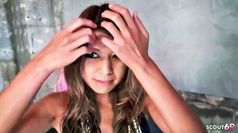 Young Japanese woman in sparkly dress posing seductively with hands in hair