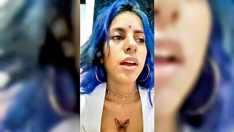 Blue-haired Indian woman with bindi and butterfly tattoo shows cleavage in open white top