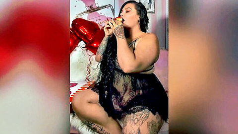 Curvy brunette in sheer black lace lingerie sipping wine with red balloon