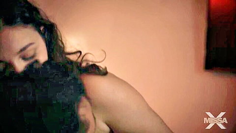Sexy brunette with bare shoulders passionately neck kissed by muscular black guy in steamy embrace
