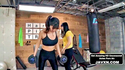 Two fit Asian gym girls in sports bras and leggings lifting dumbbells