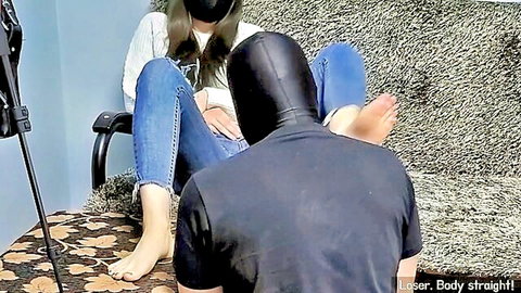 Korean femdom woman in casual jeans slaps hooded man's face with bare feet