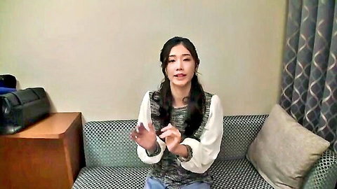 Smiling Asian woman with pigtails in casual blouse on couch, JAV style