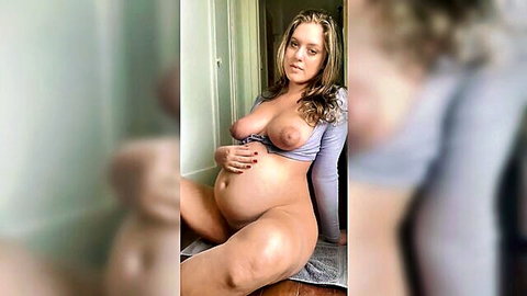 Blonde pregnant woman exposing large tits and swollen belly in solo pose