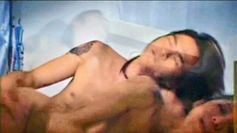 Ecstatic Thai woman with bare tits gripped passionately by tattooed muscular man's arm