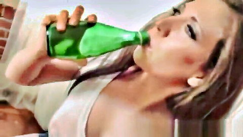 Blonde woman in low-cut white tank top drinking green bottle seductively