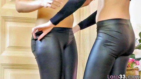 Two hot white lesbians in tight shiny leather pants grab asses in seductive tease.