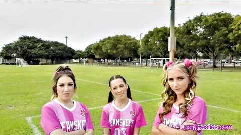 Three fit soccer girls in pink jerseys posing on field after drill