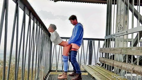 Couple in doggy style sex on public observation tower overlooking forest