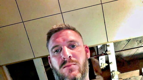 Handsome bearded gay man intense closeup stare on solo webcam in tiled room