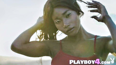 Sexy ebony babe in tight red top poses seductively outdoors with hands in hair showing big tits