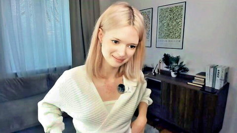 Blonde teen webcam girl smiling teasingly with cleavage in white sweater