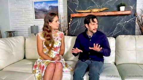 Brunette MILF in floral dress chats flirtatiously with bearded stud on couch