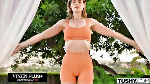 Blonde mature cougar in tight orange sports bra and shorts posing outdoors