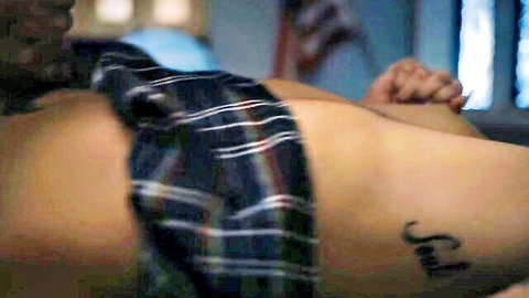 Tattooed muscular man lying naked with hard cock exposed under plaid shirt on bed