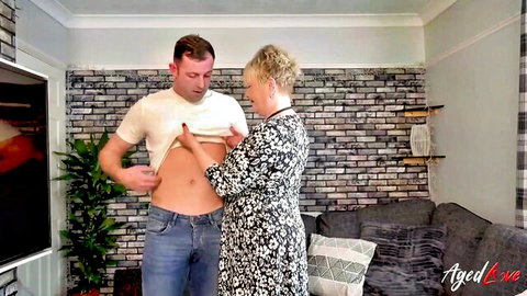 Mature blonde granny caresses young man's ripped abs teasingly
