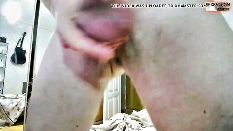 Man's fingers spreading woman's wet pink pussy lips wide open closeup on bed