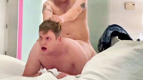Chubby blonde guy with shocked face gets hair yanked roughly by tattooed naked top in gay amateur bedroom scene