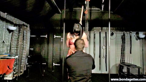 Woman suspended in intricate shibari ropes groped by man in BDSM dungeon