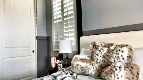 Empty modern bedroom with leopard fur pillow on bed and bedside lamp ready for solo webcam striptease