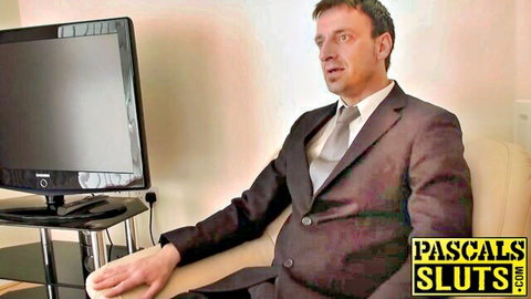 Suited man in brown suit sits on chair in Pascals Sluts studio ready for domination