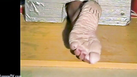 Bare foot protruding from foil-wrapped bondage box in submissive slave fetish