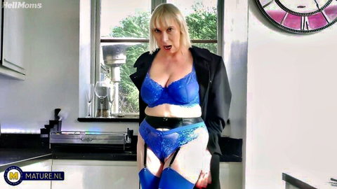Mature blonde with huge tits in blue lace bra and garter stockings teases in kitchen