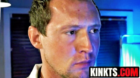 Serious handsome doctor in white shirt gazes intently in blue-lit medical room