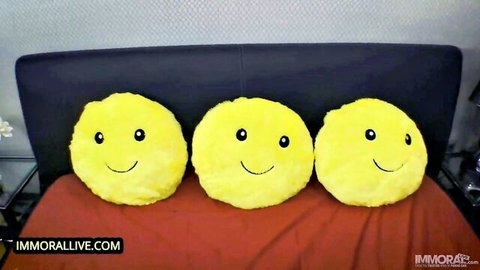 Three yellow smiley face pillows lined up on a red bedspread against black headboard