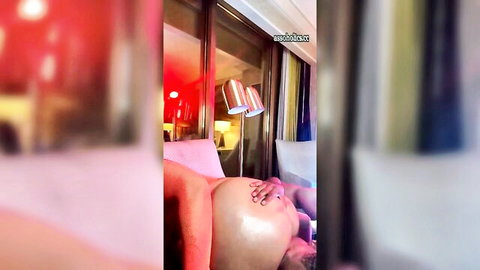 Hand caresses shiny pale pregnant belly and thigh in red-lit room