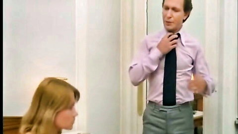 Retro blonde woman looks up at suited man adjusting tie in classic adult scene