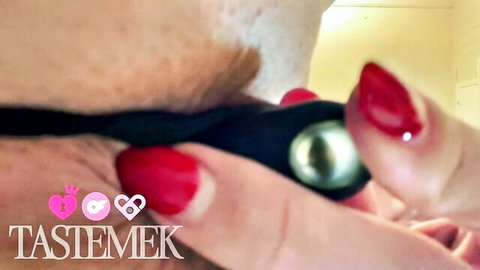 Close-up of woman with red nails inserting pearl anal plug in black panty strap, booty fetish tease
