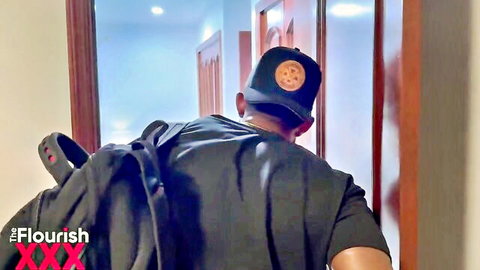 Back view of black man in backpack and cap walking into hotel hallway door