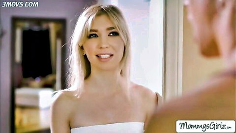 Blonde woman in white tube top smiles seductively at mirror