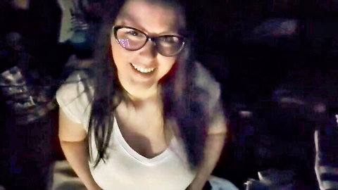 Busty brunette MILF in glasses smiles down with deep cleavage spilling from tight white tank top