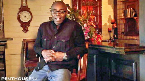 Bald Black man with glasses smiling confidently in Playboy Playhouse studio interview