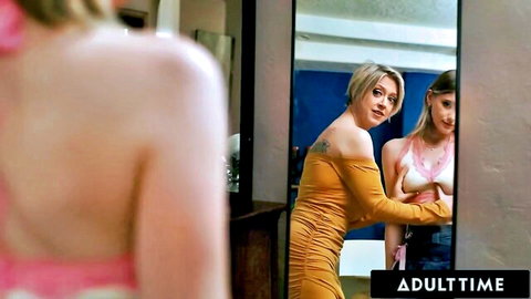 Blonde in orange dress and brunette in white bra tease seductively in bedroom mirror reflection