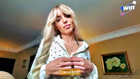 Blonde woman in open polka-dot blouse teases with cleavage, saying 'I'm alone!'