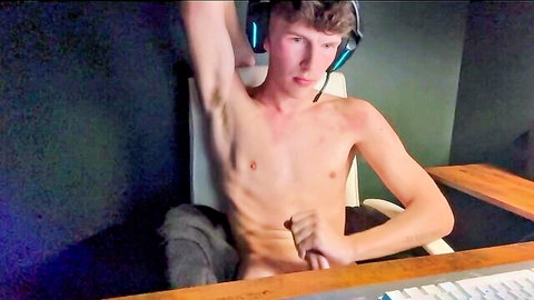 Skinny young guy in headphones strokes his cock solo while sitting nude in chair