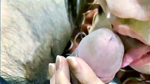 Blonde babe licks pink cock head with tongue while hand grips hairy shaft closeup