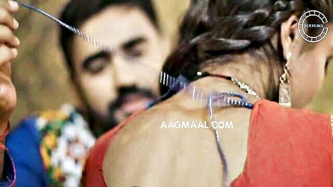 Indian girl in red saree with bare back, friend tying necklace intimately