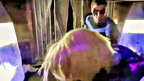Blonde superheroine in blue costume captured behind bars, dramatic purple lighting