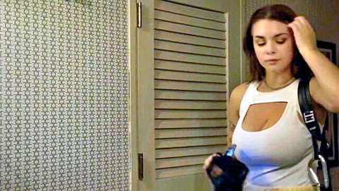 Busty brunette in revealing white cutout tank top with black harness, seductive pose