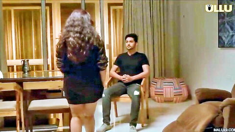 Curvy Indian woman in short black dress facing seated man, Kavita Bhabhi ULLU series