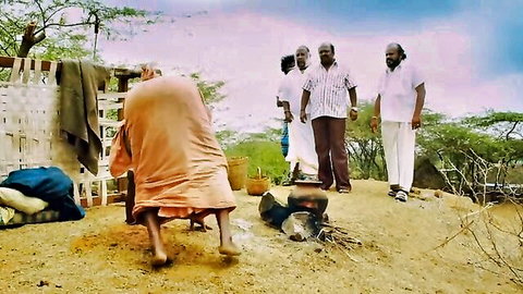 Group of Indian men in traditional attire gathered outdoors in rural scene