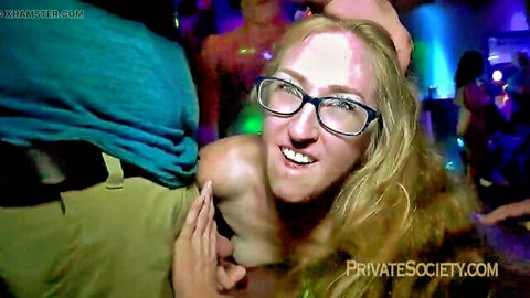 Topless blonde with glasses smiles as man gropes her bare tits in neon club crowd