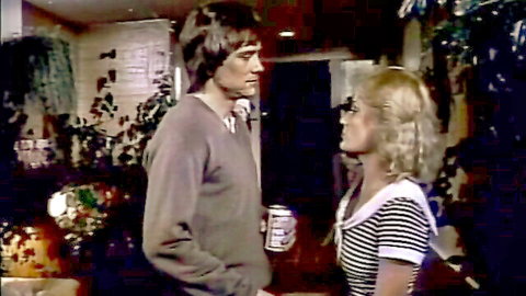 Vintage 1983 Tomboy scene: blonde in striped sailor top chats with long-haired man in sweater