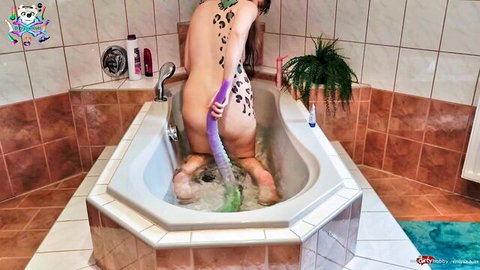Tattooed babe with leopard spots rides thick purple dildo in bathtub, ass up pussy stuffed