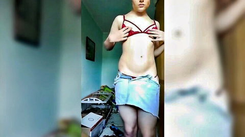 Slim crossdresser in red lace bra and short denim skirt teasing striptease